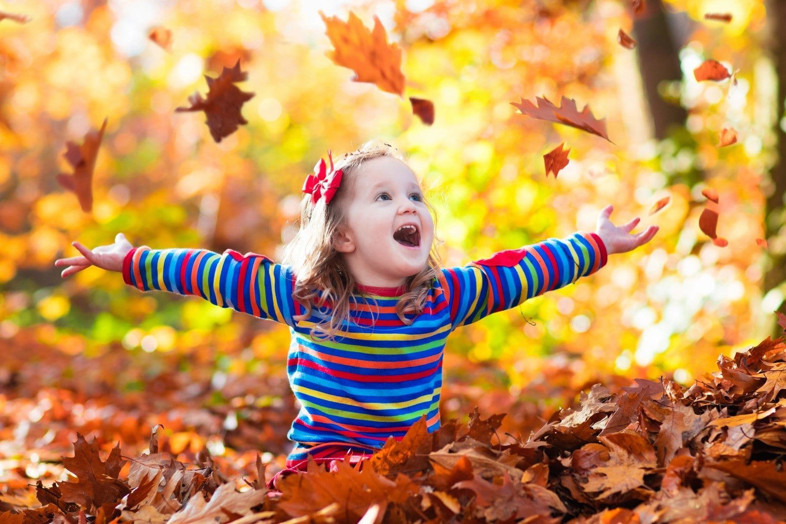 Young girl playing in fall leaves